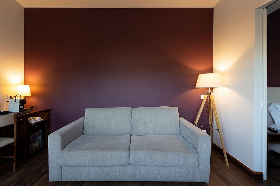 un sofá y una lámpara en una habitación con una pared morada