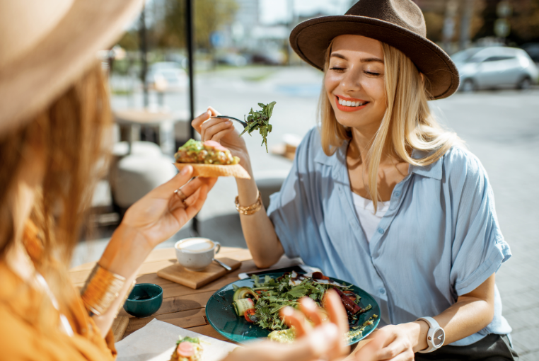 dos mujeres están sentadas en una mesa comiendo comida