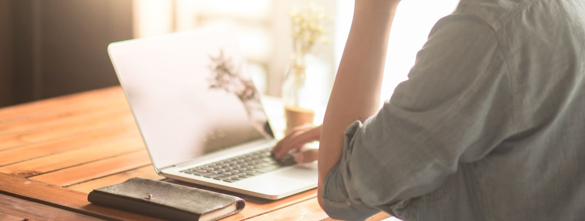 a person is typing on a laptop with a wallet next to it