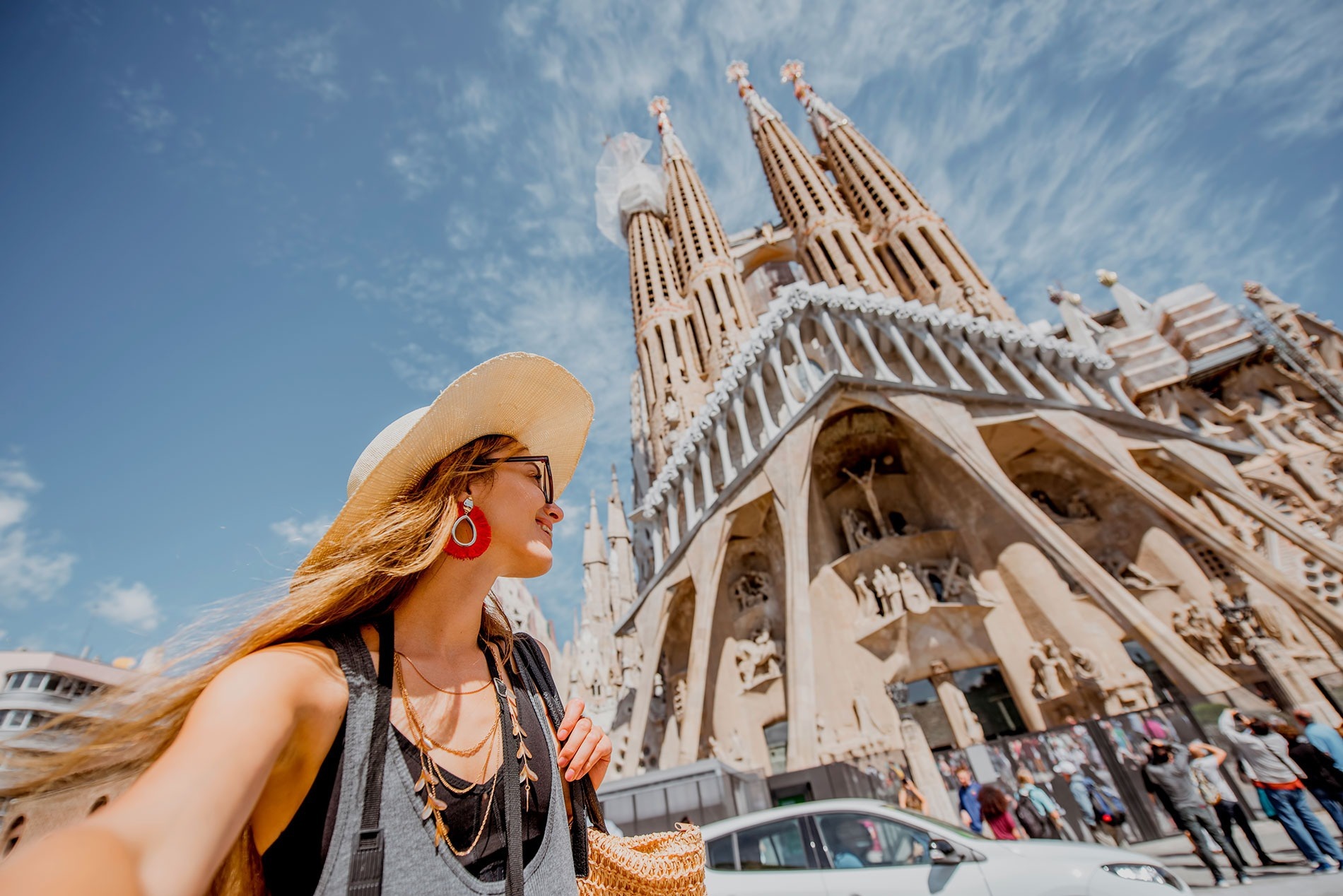 una mujer con un sombrero y aretes rojos se para frente a una catedral