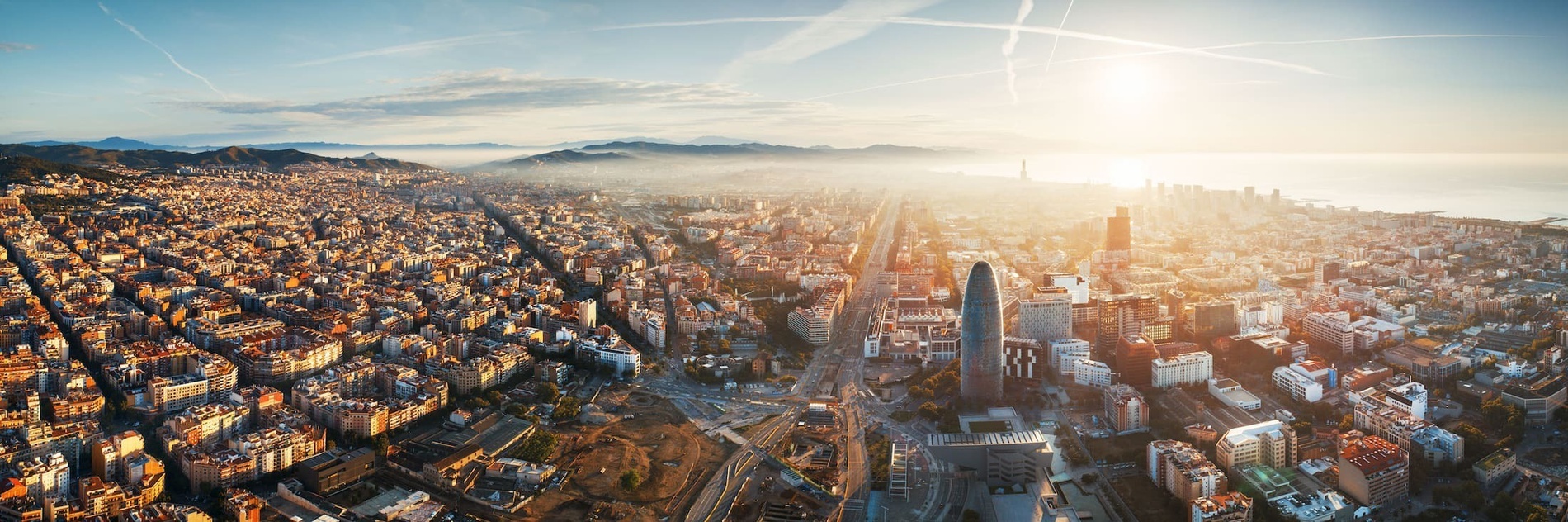 an aerial view of a city with the sun shining through the clouds