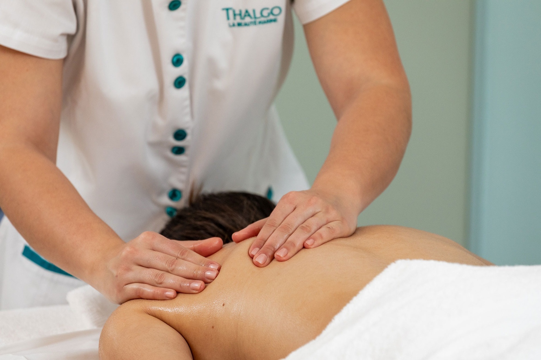 uma mulher está dando um massagem a um homem em um salão de beleza thalgo