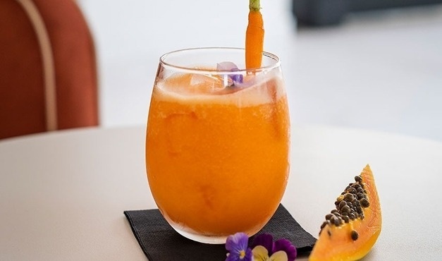 um copo de suco de laranja com uma cenoura nele