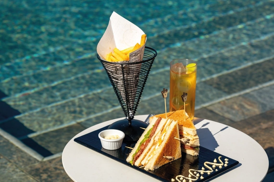 sanduíche e batatas fritas em uma mesa ao lado de uma piscina