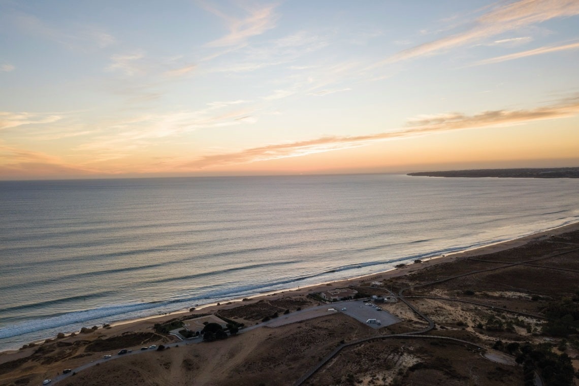 uma vista aérea de uma praia ao pôr do sol