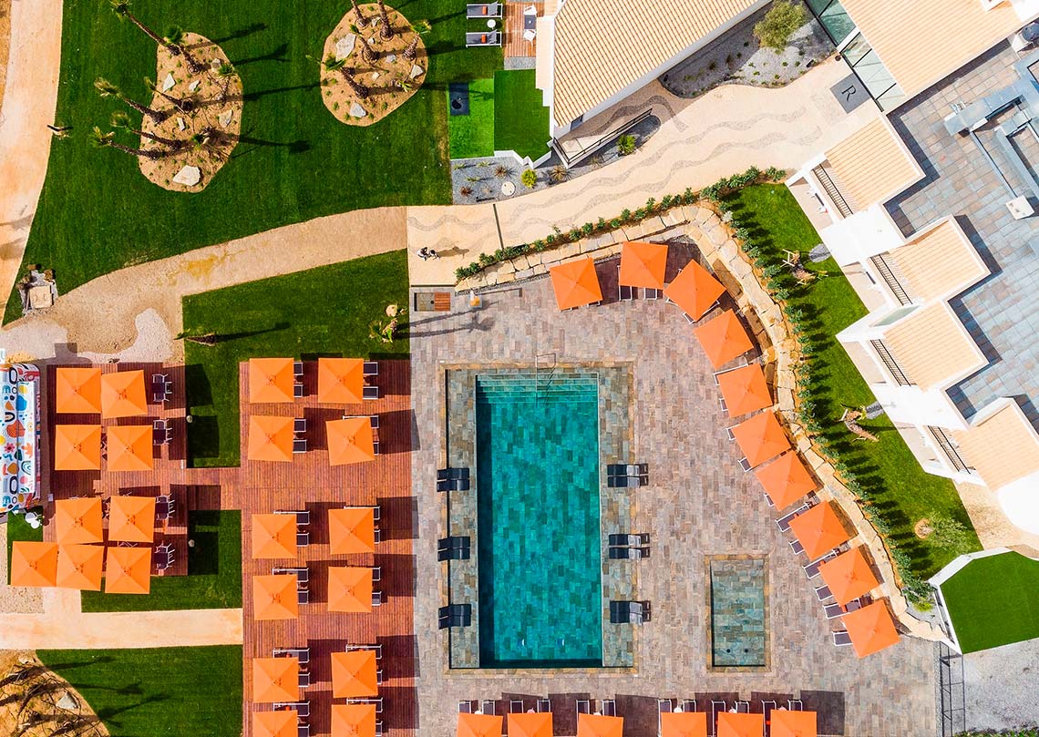 Vista aérea de piscina y tumbonas con sombrillas naranjas. Localización y Contactos | Regency Salgados Hotel & Spa