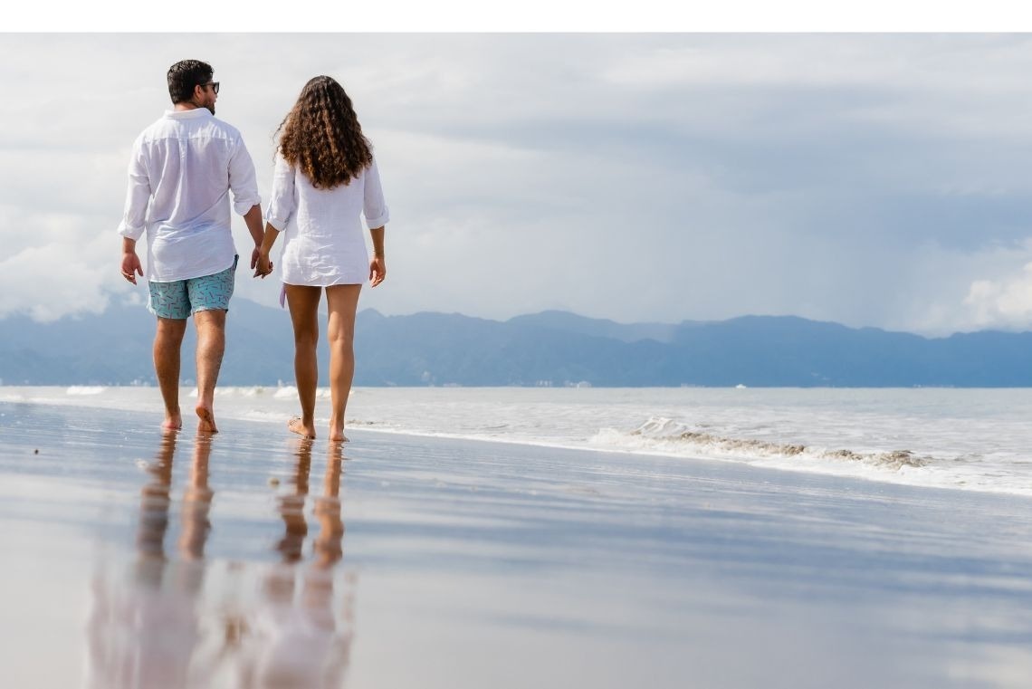 un hombre y una mujer caminan por la playa con la palabra ventas de enero en el fondo