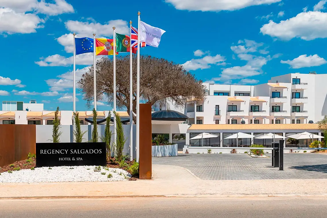 Entrada do Regency Salgados Hotel & Spa com bandeiras e paisagismo.