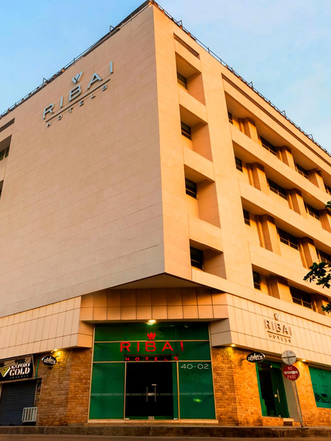 Hotel Ribai Corporativa: fachada moderna con letrero luminoso y entrada verde.