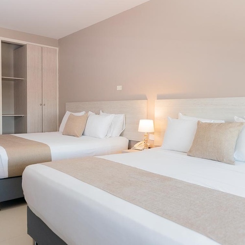 Habitación de hotel con dos camas, ideal para viajes de negocios en Hotel Ribai Corporativa.