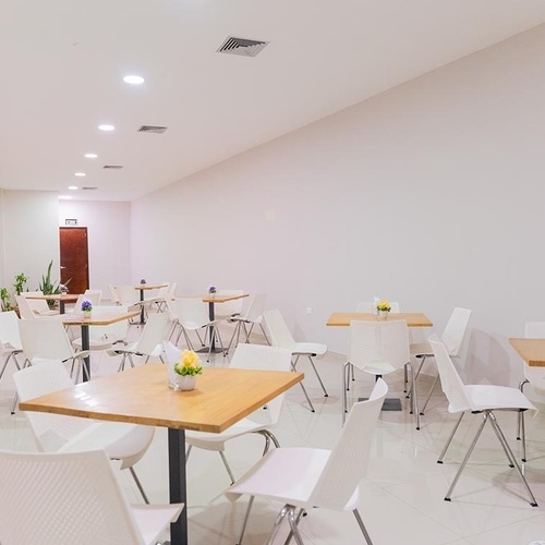 Moderno comedor del Hotel Ribai Corporativa, con mesas de madera y sillas blancas.