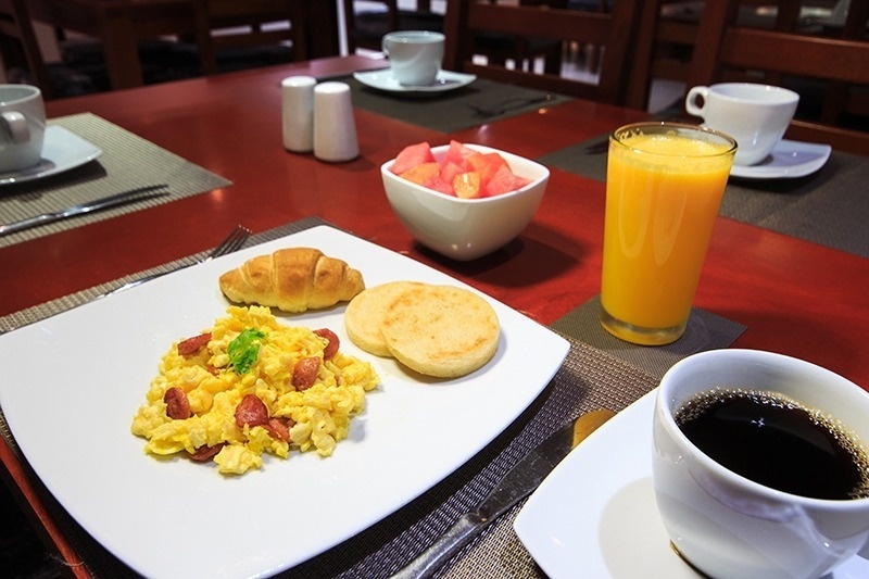 Desayuno en Hotel Ribai Corporativa: huevos revueltos, croissant, arepas, jugo y café.
