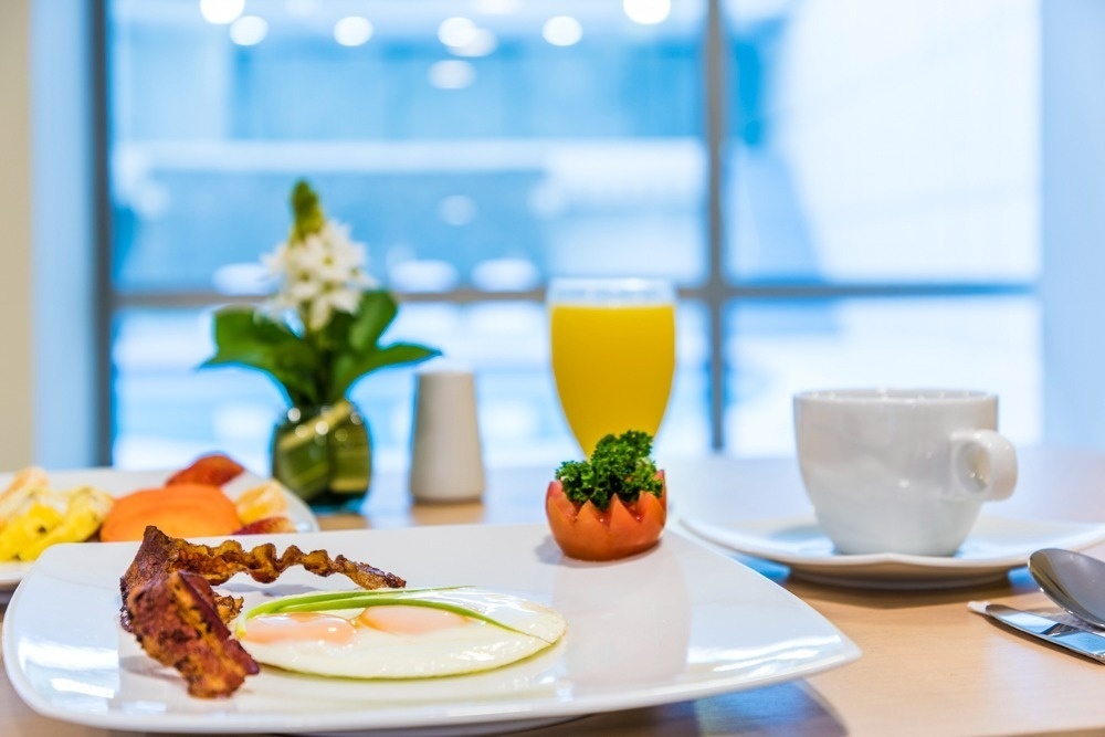 Desayuno de Hotel Ribai Corporativa: huevos, tocino, fruta y jugo.