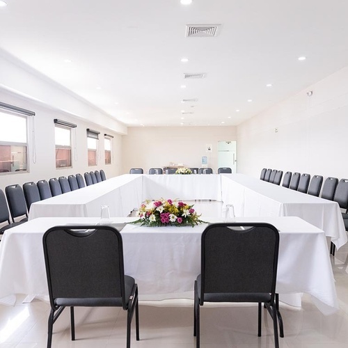 Sala de juntas en Hotel Ribai Corporativa, dispuesta en U con sillas y centro floral.