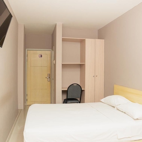 Habitación de hotel limpia y sencilla con cama, escritorio y TV en Hotel Ribai Corporativa.
