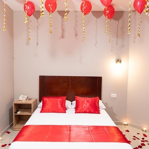Habitación romántica con globos rojos y pétalos en Hotel Ribai Corporativa.