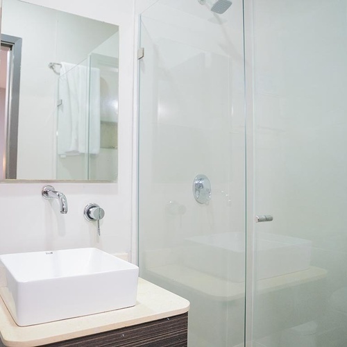 Baño moderno en Hotel Ribai Corporativa con lavabo, ducha y espejo.