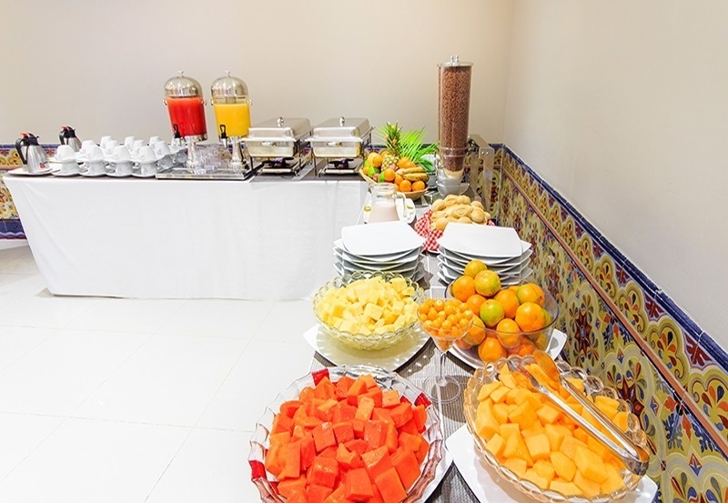 Buffet de desayuno en Hotel Ribai Corporativa: jugos, frutas frescas, pan y cereales.