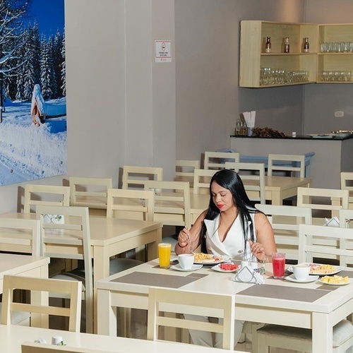 Desayuno en Hotel Ribai Corporativa: mujer disfrutando su comida junto a cuadro invernal.