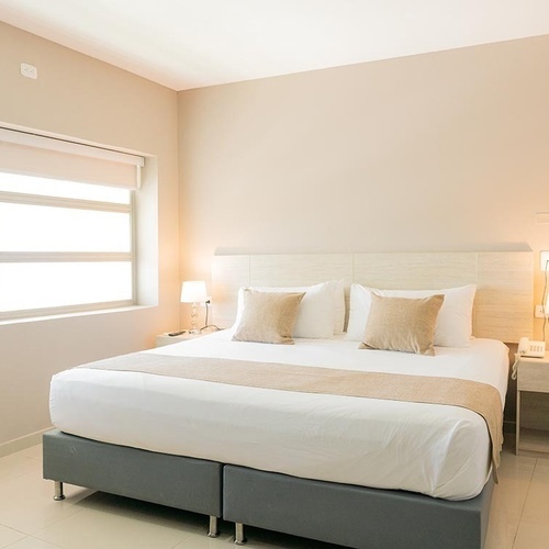 Habitación de lujo en Hotel Ribai Corporativa: cama king, ventana y mesitas de noche.