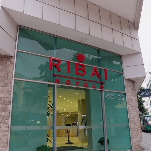 Hotel Ribai Corporativa: Fachada moderna con letrero rojo y entrada de cristal.