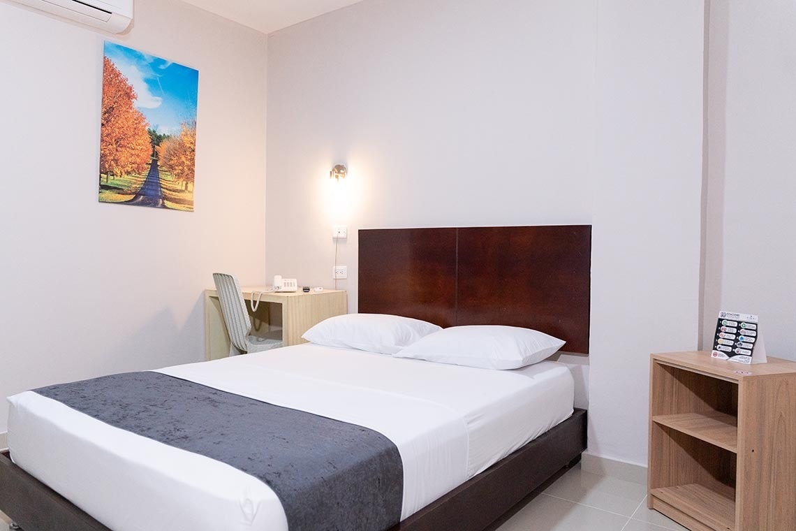 Habitación de Hotel Santa Marta | Centro Histórico y Confort | Ribai Hotels: Cama doble, escritorio y cuadro de paisaje otoñal.