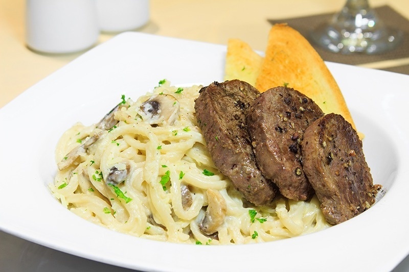 Filete de res con pasta cremosa y pan tostado, ideal para una cena en Hotel Ribai Corporativa.