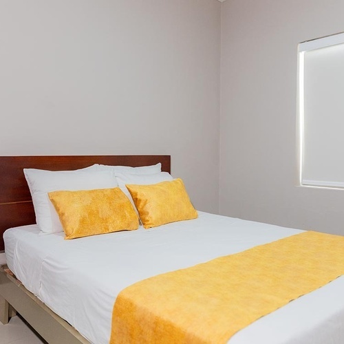 Habitación cómoda en Hotel Ribai Corporativa con cama doble y detalles amarillos.