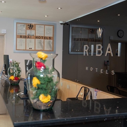 Recepción Hotel Ribai Corporativa con flores decorativas y señalización.