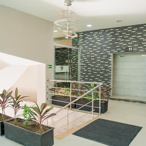 Recepción y escalera del Hotel Ribai Corporativa, con plantas y ascensor.