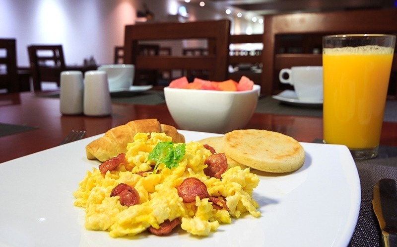 Desayuno Hotel Ribai Corporativa: huevos revueltos, croissant, arepas y jugo.