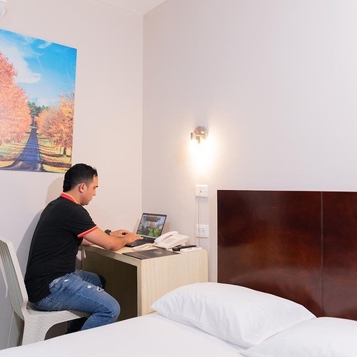 Hombre trabajando en laptop en su habitación de Hotel Ribai Corporativa.