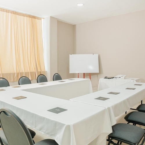 Sala de juntas corporativas Hotel Ribai, con mesas en U y sillas negras.