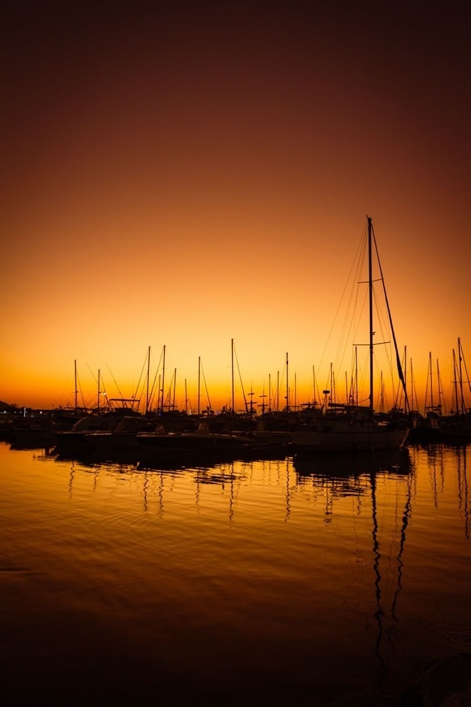 Atardecer dorado en el puerto deportivo de Hotel Ribai Corporativa, veleros en silueta.