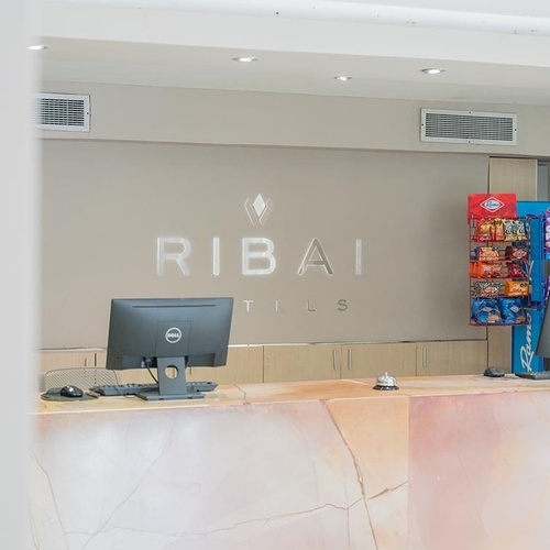 Recepción del Hotel Ribai Corporativa con computadoras y snacks.