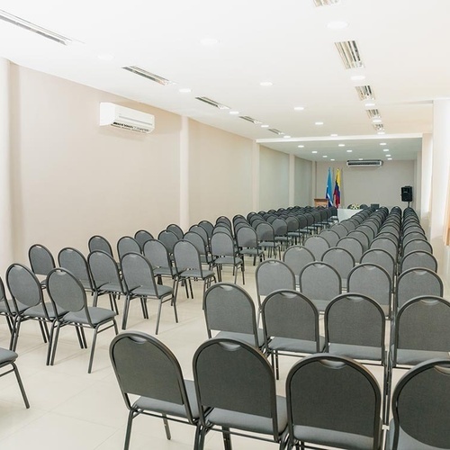 Sala de conferencias vacía en Hotel Ribai Corporativa, con asientos grises dispuestos.