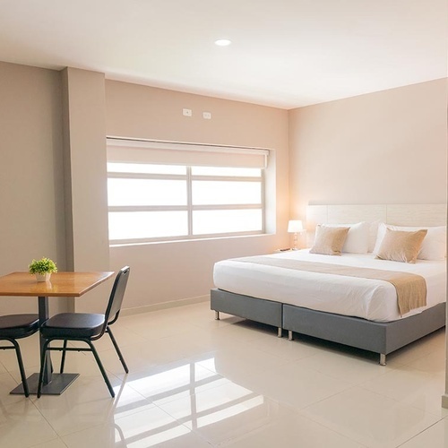 Habitación moderna de Hotel Ribai Corporativa con cama King, mesa y TV.