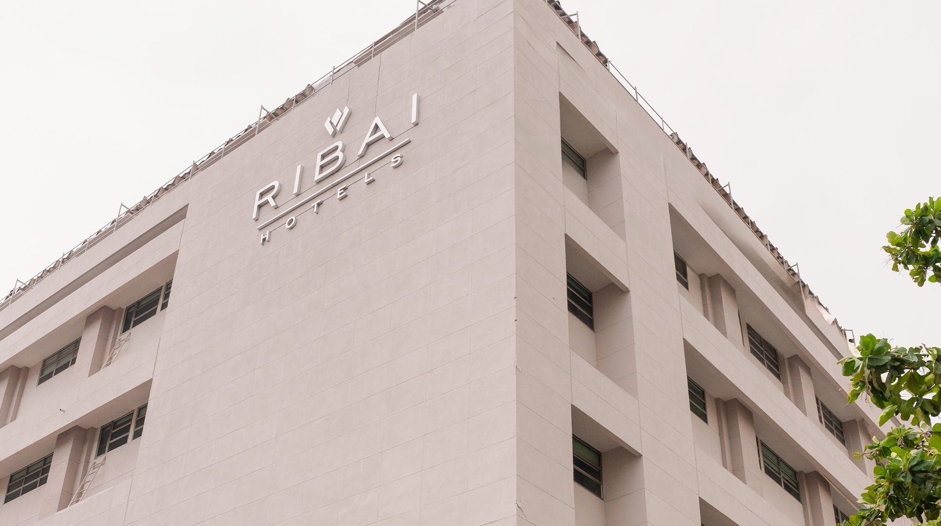 Hotel Barranquilla | RIBAI Hotels: Fachada moderna y luminosa con el logo de RIBAI HOTELS. ¡Reserva oficial!