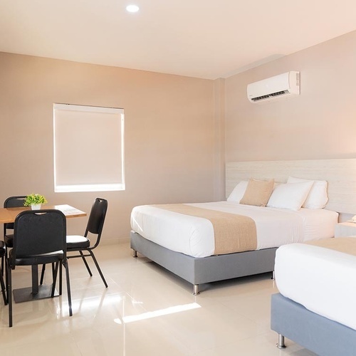 Habitación de Hotel Ribai Corporativa con dos camas, escritorio y silla.