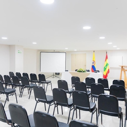 Sala de conferencias con sillas y pantalla en Hotel Ribai Corporativa.