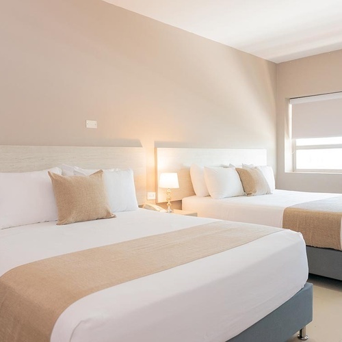 Habitación doble en Hotel Ribai Corporativa con dos camas, ropa de cama blanca y acentos tierra.