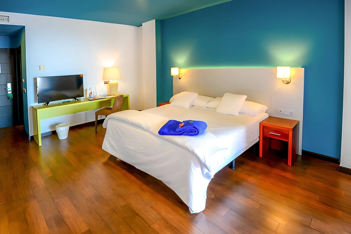 una habitación oscura con una cama y un jarrón de flores