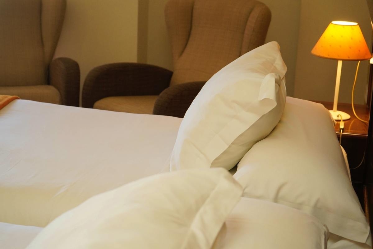 un primer plano de una cama con almohadas y una lámpara