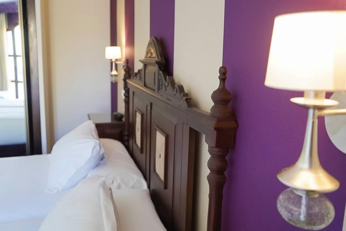 una cama en una habitación con paredes moradas y blancas