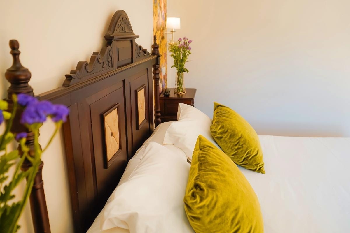 una cama con dos almohadas amarillas y un reloj en la cabecera