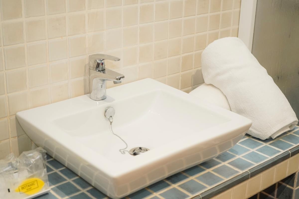 un lavabo blanco con un grifo y una toalla blanca