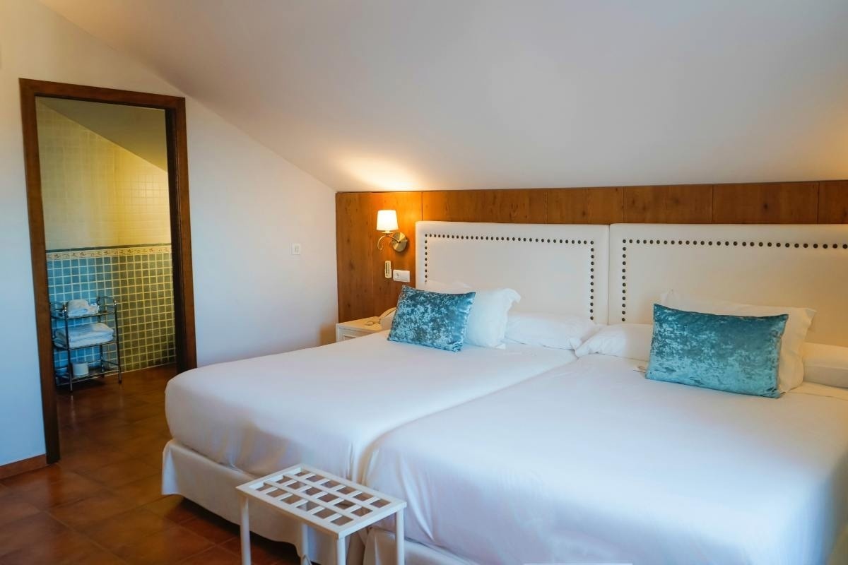 una habitación con dos camas blancas y almohadas azules