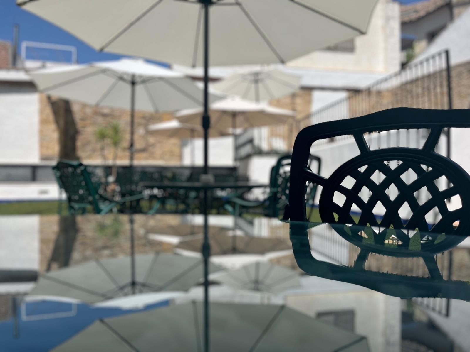 una mesa de vidrio con sillas y sombrillas en el fondo