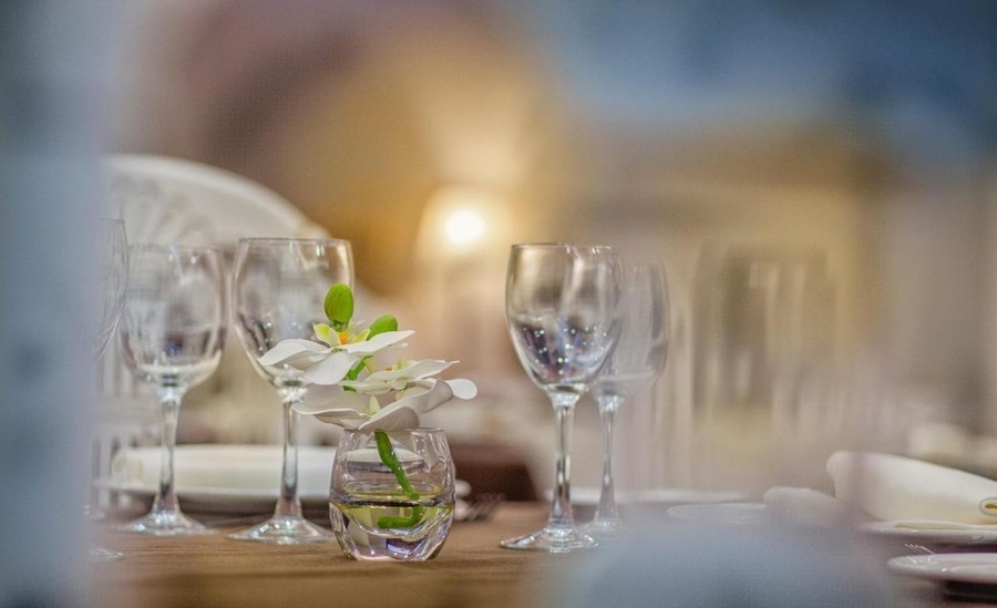 una mesa con copas de vino y una flor en un jarrón