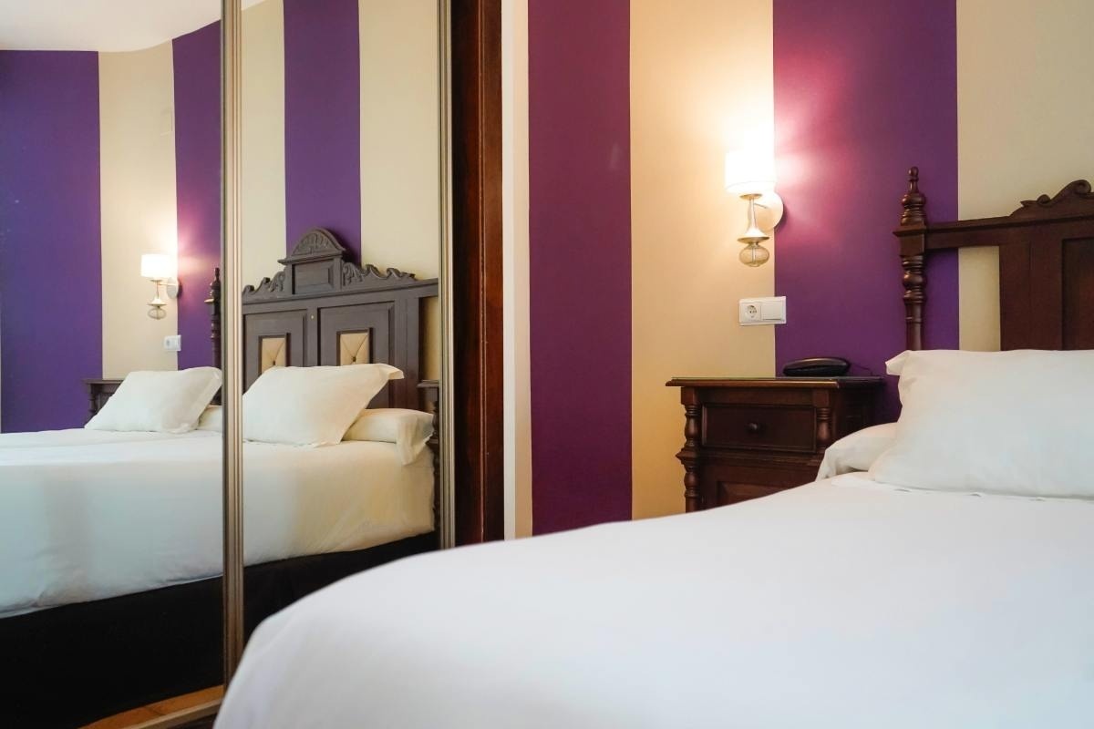 una cama en una habitación con paredes moradas y blancas